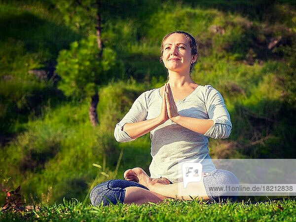 Meditation und Entspannung Yoga im Freien  junge Frau meditiert und entspannt in Padmasana Lotus Pose) mit Namaste Mudra auf grünem Gras im Wald. Vintage Retro-Effekt gefiltert Hipster-Stil Bild