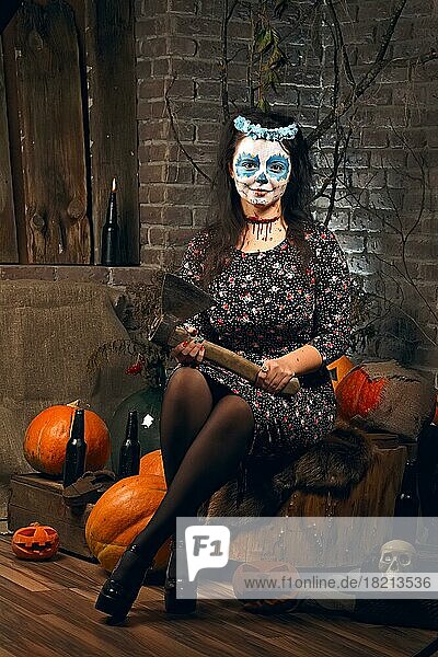 Junge Frau mit Axt und Zuckerschädel Make-up während Halloween. Gesichtsbemalung Kunst