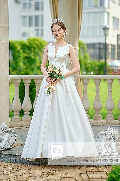 Portrait of pretty bride with coronet in hair outdoor near ceremony pavilion