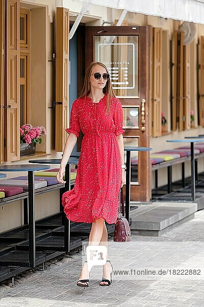 Hübsches Mädchen in rotem Sommerkleid zu Fuß auf der Straße in der Altstadt