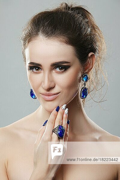 Porträt eines schönen Modemodells mit Bijouterie. Ohrringe  Fingerring und Halskette mit großen Kristallen. Frische Haut und natürliches Make-up