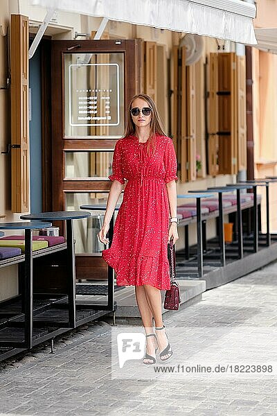 Hübsches Mädchen in rotem Sommerkleid zu Fuß auf der Straße in der Altstadt