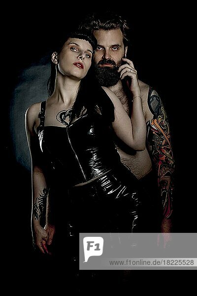 BDSM Paar  Mann mit Tattos und Frau in Lack und Latex Outfit