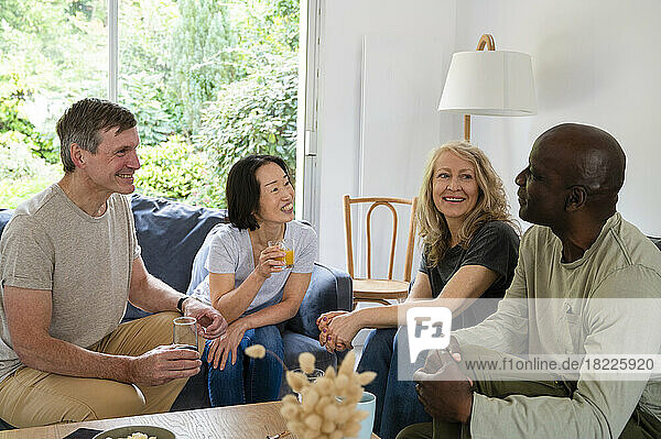 Portrait of two diverse couples chatting while having a drink indoors