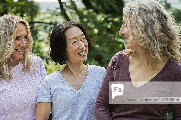 Three middle aged women having a friendly conversation in their backyard
