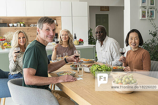 Group of diverse senior friends gathered together for lunch in the kitchen