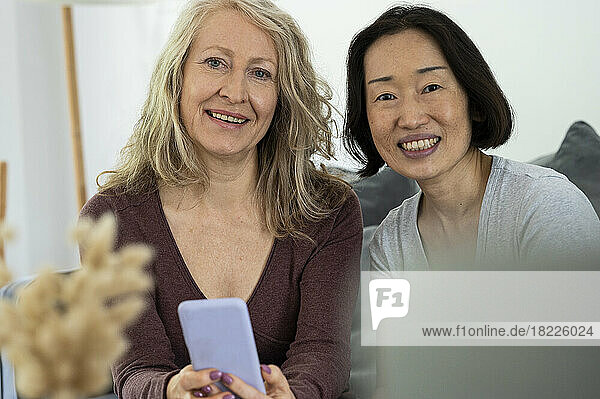 Portrait of two senior female friends looking at camera while having a good tme together at home