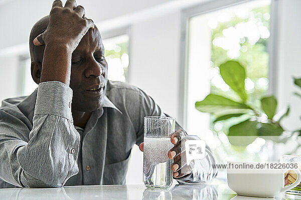Middle-aged African-American man with headache taking his medicine