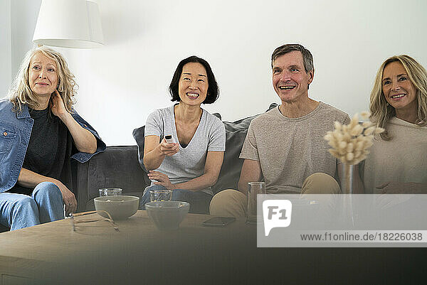 Diverse group of senior friends sitting on sofa watching TV