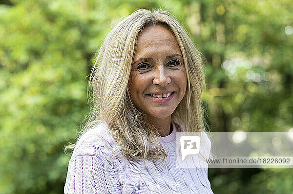 Mid-shot portrait of middle age woman looking at camera while posing outdoors