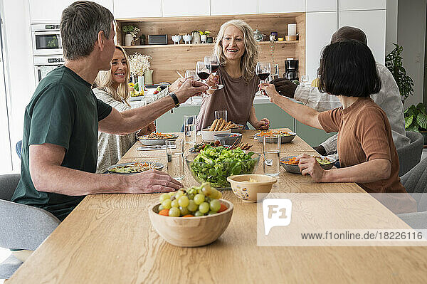 Group of diverse senior friends making a toast while having dinner at home