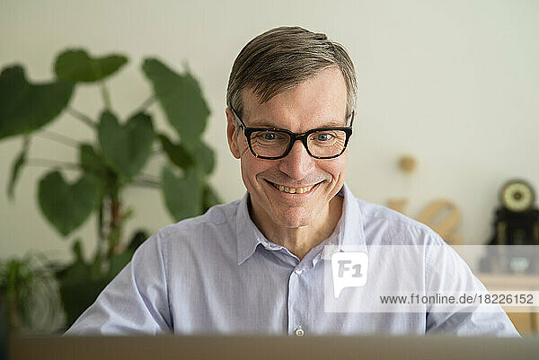 Senior man smiling while using laptop at home