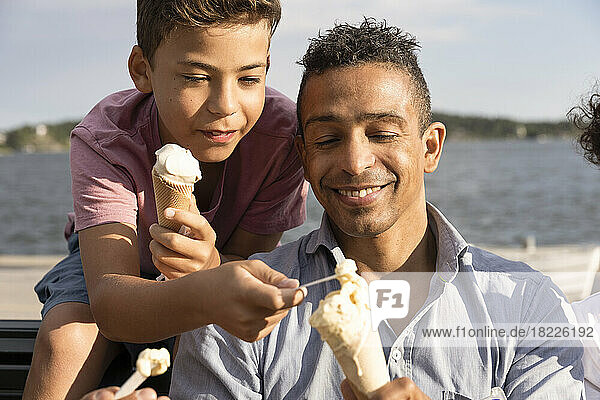 Happy father sharing ice cream with son during summer vacation