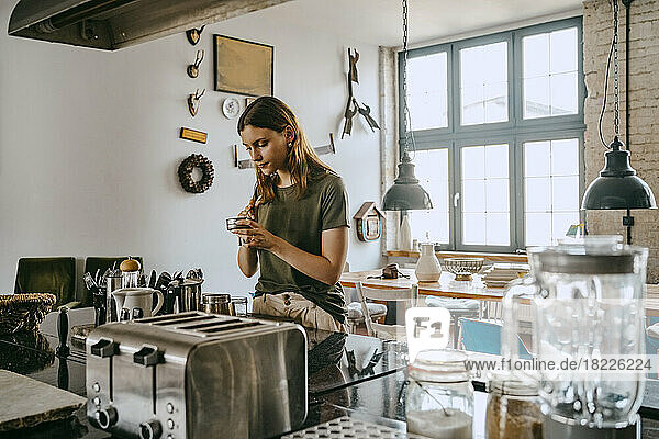 Junge Unternehmerin bereitet Kaffee zu  während sie an der Theke im Studio steht