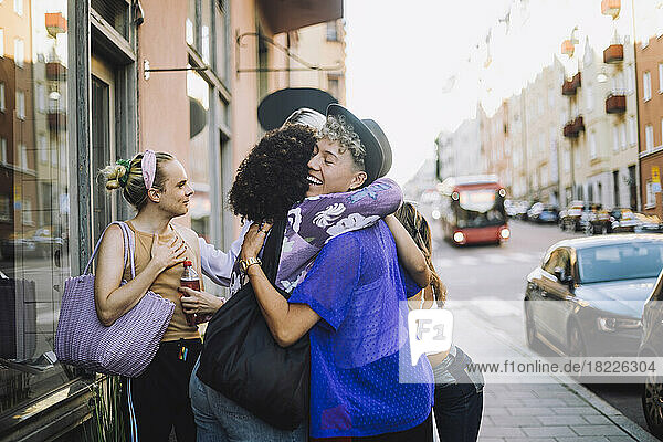 Glücklicher junger Mann mit geschlossenen Augen  der eine Freundin in der Stadt umarmt