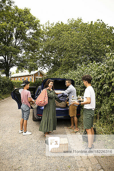 Eine Familie hilft sich gegenseitig beim Einladen von Picknickutensilien in den Kofferraum