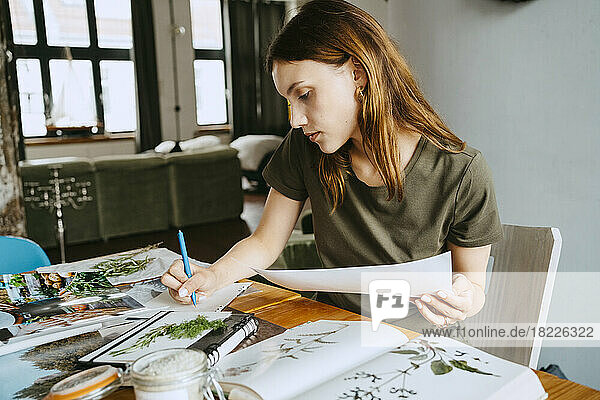 Weiblicher Food-Stylist schreibt auf Papier und hält ein Foto im Studio