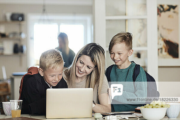 Happy mother with excited sons watching laptop at home