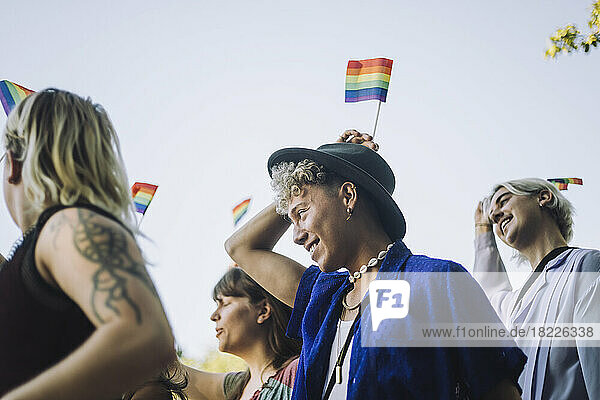 Ein lächelnder junger Mann genießt mit Freunden die LGBTQIA-Parade