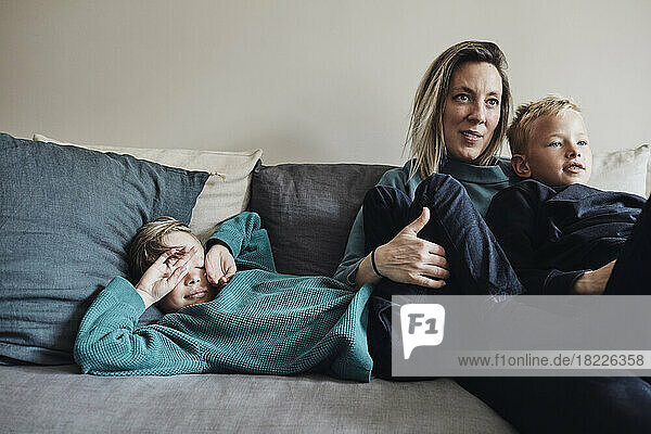 Woman spending leisure time with sons on sofa at home