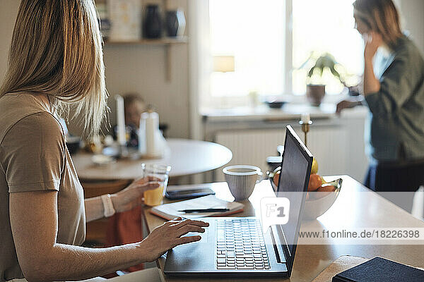 Female freelancer looking away while sitting with laptop at home