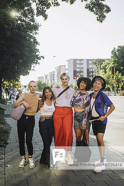 Porträt in voller Länge von lächelnden jungen LGBTQIA-Freunden  die auf einem Fußweg stehen