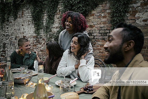 Lächelnde multirassische männliche und weibliche Freunde  die sich während einer Dinnerparty miteinander unterhalten