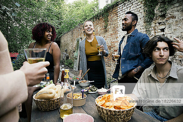 Männliche und weibliche Freunde verschiedener Rassen genießen Essen und Getränke auf einer Gartenparty