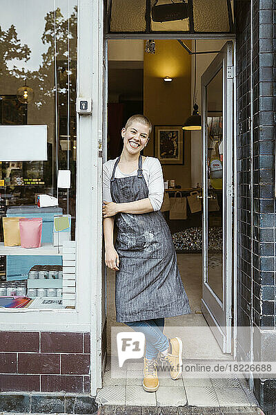 Porträt einer glücklichen Besitzerin  die an der Ladentür lehnt