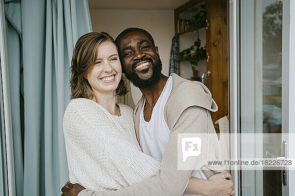 Glückliches multirassisches Paar  das sich an der Tür umarmt