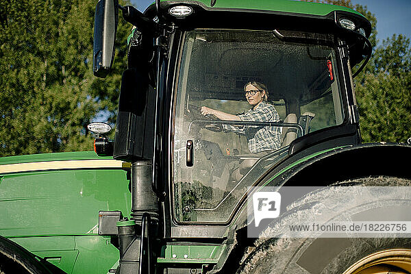 Bäuerin fährt Traktor an einem sonnigen Tag
