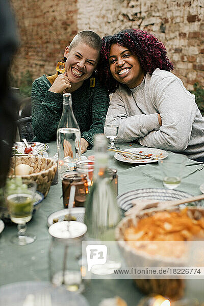 Porträt von multirassischen Freundinnen am Esstisch während einer Dinnerparty