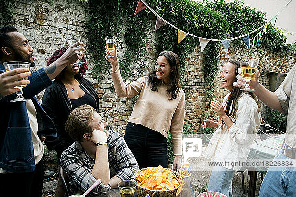 Multirassische männliche und weibliche Freunde stoßen mit Getränken an  während sie auf einer Dinnerparty im Hinterhof feiern