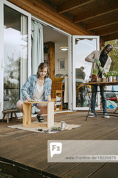 Junge Frau baut Möbel mit Mann bei der Gartenarbeit auf der Veranda