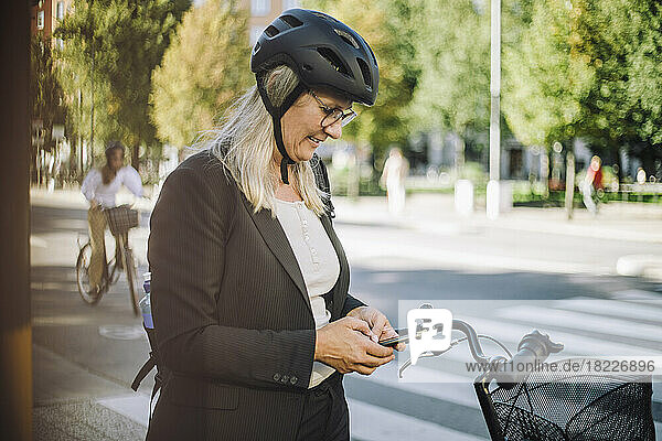 Businesswoman wearing cycling helmet using smart phone