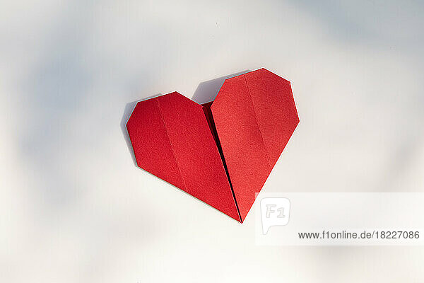 Red origami heart on white background