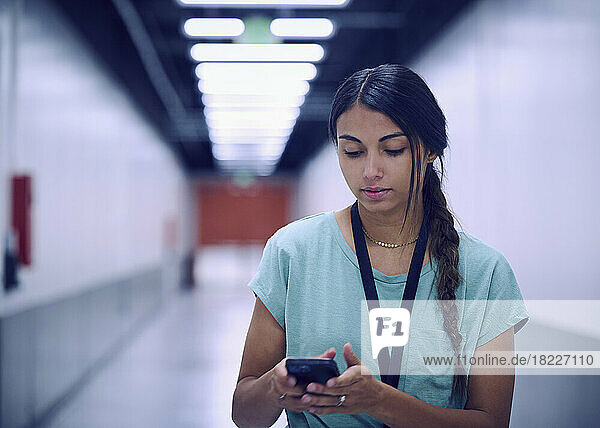 Female technician looking at smart phone in data center