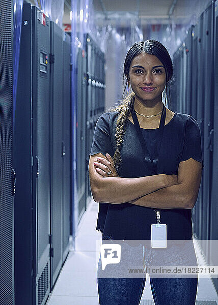 Portrait of smiling female technician standing in server room