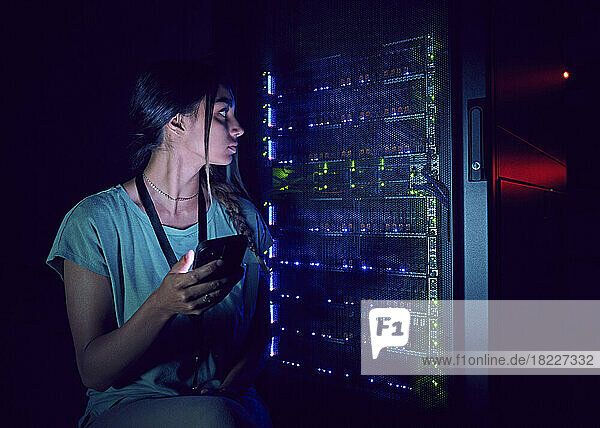 Technician with smart phone in server room