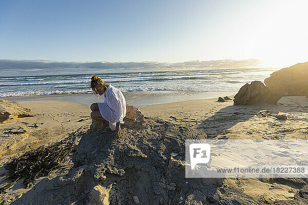 South Africa  Hermanus  Teenage girl (16-17) sitting on rocks on beach