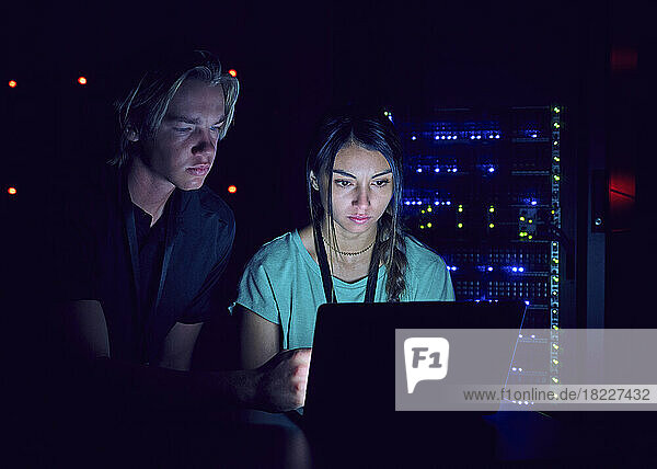 Technicians using laptop in server room