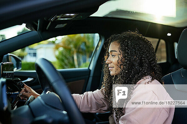 Young woman with curly hair using GPS system in car