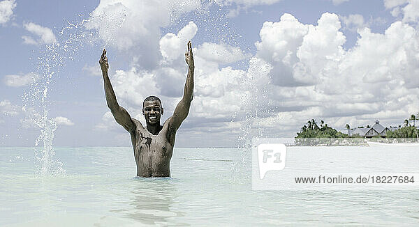 Happy black man playing with sea water
