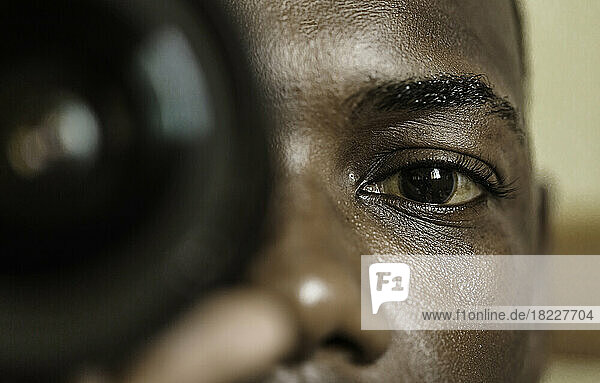 Black photographer looking at camera through lens