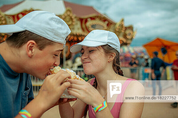 Teen kids at a carnival eating a funnel cake