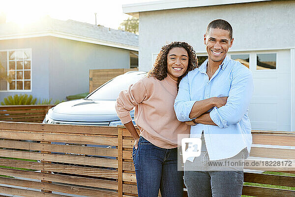 Portrait of smiling heterosexual couple against house in back yard