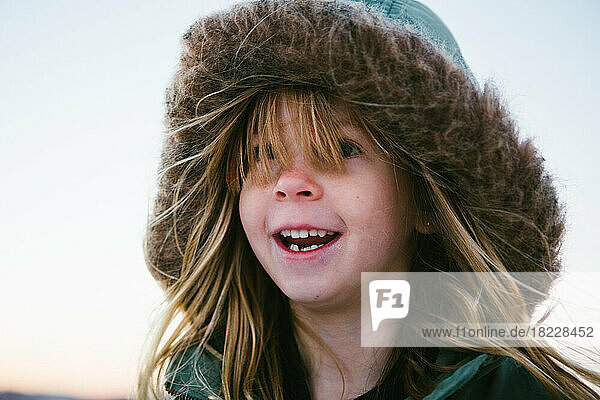 Young blond girl in warm winter coat outside smiling in winter