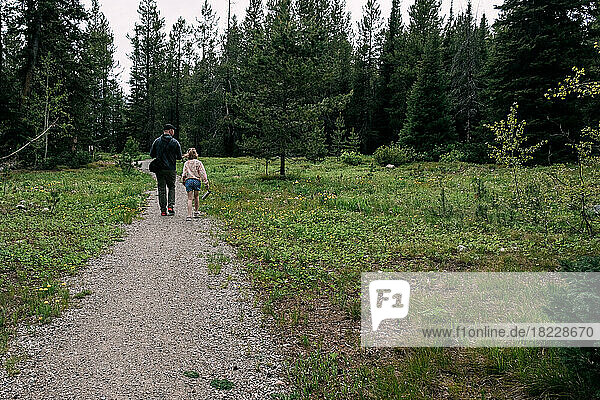 Father and daughter walking on hiking trail in forest