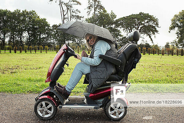 retired woman on a mobility scooter outside in the rain