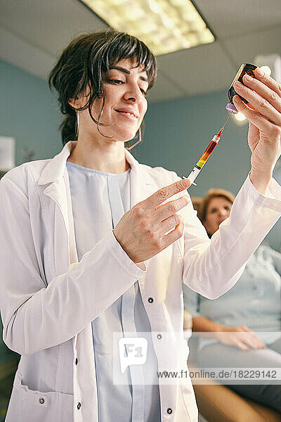 Female doctor preparing?botox?injection  patient in background